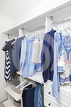 Beach blue clothes hanging in white wardrobe in home