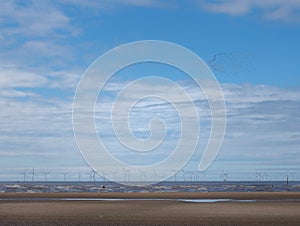 The beach at blundell sands in sefton near southport with waves braking on the beach and the wind turbines at burbo bank visible