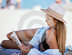 Beach, book and woman reading on holiday, vacation or summer travel in nature outdoor. Relax, novel and person at sea or