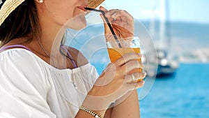 In a beach cafe gazebo on the pier, brunette woman enjoys her orange juice. Essence of summertime, holiday bliss