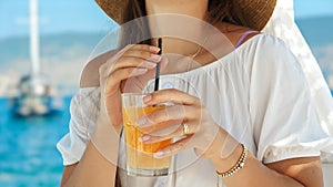 In a beach cafe gazebo on the pier, a brunette woman enjoys her orange juice with pure delight. Essence of summertime