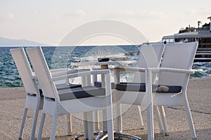 Beach cafe with sea view at sunset, empty table, four chairs, vacant for guests.