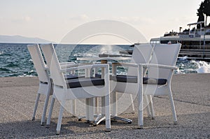 Beach cafe with sea view at sunset, empty table, four chairs, vacant for guests.