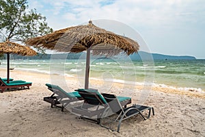 Beach calm scene with sunbeds and straw umbrellas under coconut palms close to Caribbean sea. Tropical paradise with chaise