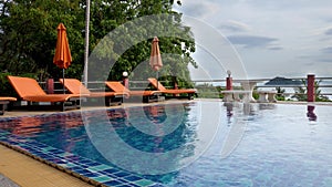 Beach chair and orange umbrella near swimming pool with on resort villa