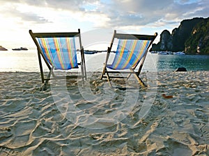 Beach chair on the sand beach with boat ,mountain and blue sky background