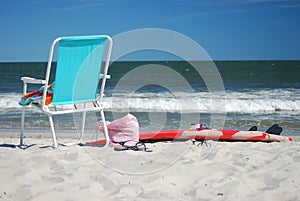 Beach chair and surfboard on beach