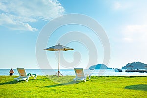 Beach chairs and beach umbrellas are on the lawn at the beach.Sea view and bright sky
