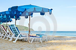 Beach chairs and blue umbrellas on a sandy beach against the backdrop of the sea