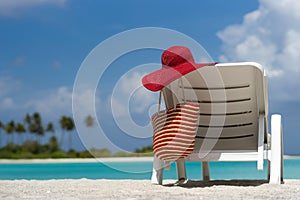 Beach chairs with hat on white sandy beach.