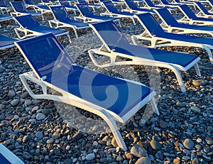 Beach chairs. Lots of empty sunbeds on the pebbles. The concept of commerce on the beach. Sunbed rental at the resort. At sunset