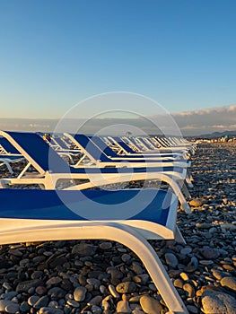 Beach chairs. Lots of empty sunbeds on the pebbles. The concept of commerce on the beach. Sunbed rental at the resort. At sunset