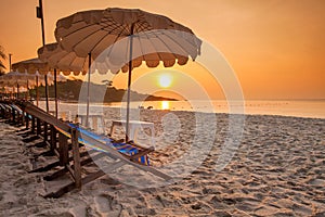 Playa sillas rango a través de atardecer 