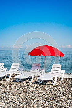 Beach chairs and red umbrella on shingle beach