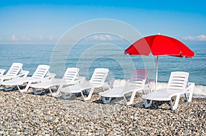 Beach chairs and red umbrella on shingle beach