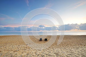 The beach chairs on sand beach during sunrise or sunset