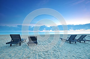 The beach chairs on sand beach during sunrise or sunset