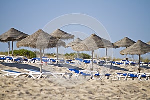 Beach chairs with straw umbrellas