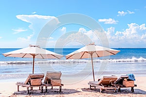 Beach with chairs. Sunbeds and umbrella at Bali coast. Luxury beach background.