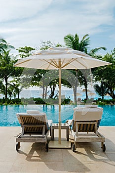 Beach chairs at a swimming pool at a luxury hotel, sunbed chair and umbrella