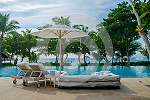 Beach chairs at a swimming pool at a luxury hotel, sunbed chair and umbrella