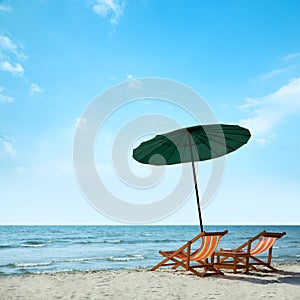 Beach chairs and umbrella on beach.