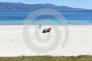 Beach chairs and umbrella on a beach with white sand and turquoise water. Rias Baixas, Galicia, Spain.