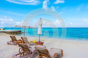 Beach chairs with umbrella at Maldives island with white sandy b