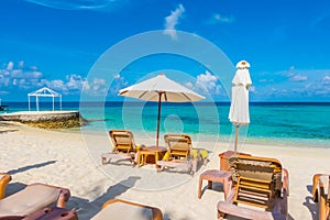 Beach chairs with umbrella at Maldives island with white sandy b