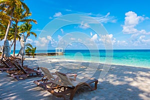 Beach chairs with umbrella at Maldives island with white sandy b