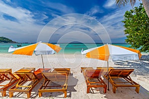 Beach chairs, umbrella and palms on the beautiful beach for holidays and relaxation at Koh Lipe island, Thailand