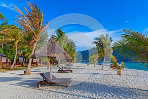 Beach chairs, umbrella and palms on the beautiful beach for holidays and relaxation at Koh Lipe island, Thailand