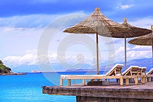 Beach chairs with umbrella, wood terrace, beautiful tropical sea view