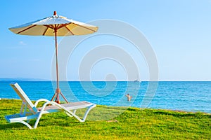 Beach chairs and beach umbrellas are on the lawn at the beach.Sea view and bright sky photo