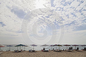 Beach chairs, umbrellas on sea sand sky and cloud background.