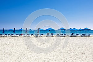 Beach chairs and umbrellas on white sand sea beach