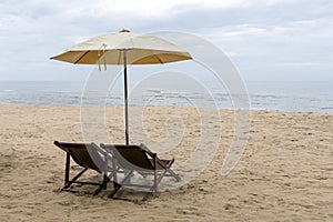 Beach chairs under a cream umbrella on the fine beach.
