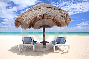 Beach chairs under palapa thatched umbrella