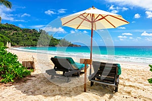 Beach chairs under umbrella on tropical beach