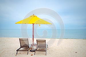 Beach chairs under a yellow umbrella