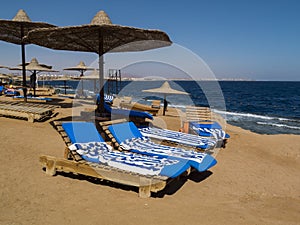 Beach chairs on the white beach with blue sky