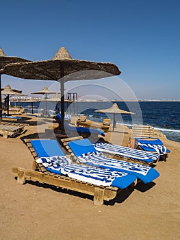 Beach chairs on the white beach with blue sky