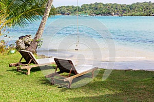 Beach chairs on the white sand beach with blue sky and sun