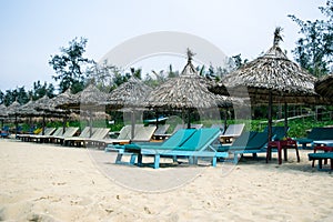 Beach chairs on the white sand beach with cloudy blue sky and sun