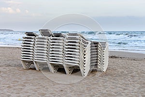 Beach chaise lounges stacked in a row on the beach