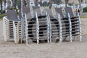 Beach chaise lounges stacked in a row on the beach