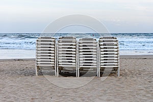 Beach chaise lounges stacked in a row on the beach