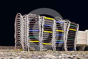 Beach chaise lounges stacked in a row on the night beach