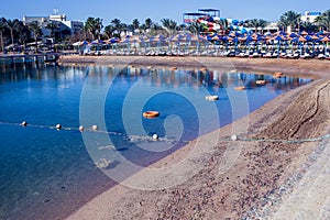 Beach with chaise lounges standing in line on beige sand. Holiday and travel concept