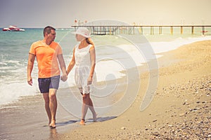 Beach couple walking on romantic travel honeymoon vacation summer holidays romance. Young happy lovers, Caucasian woman and man ho